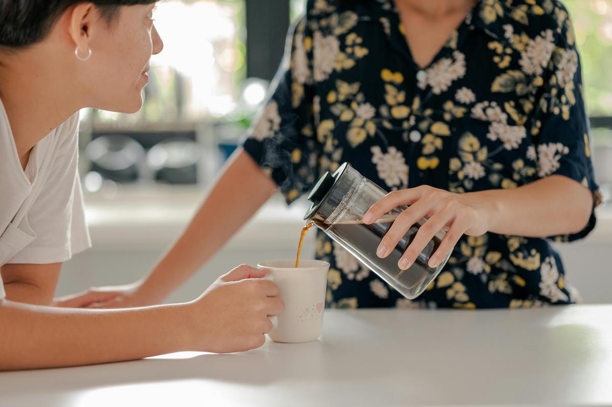 Eine Frau gießt einer anderen Frau Kaffee ein.